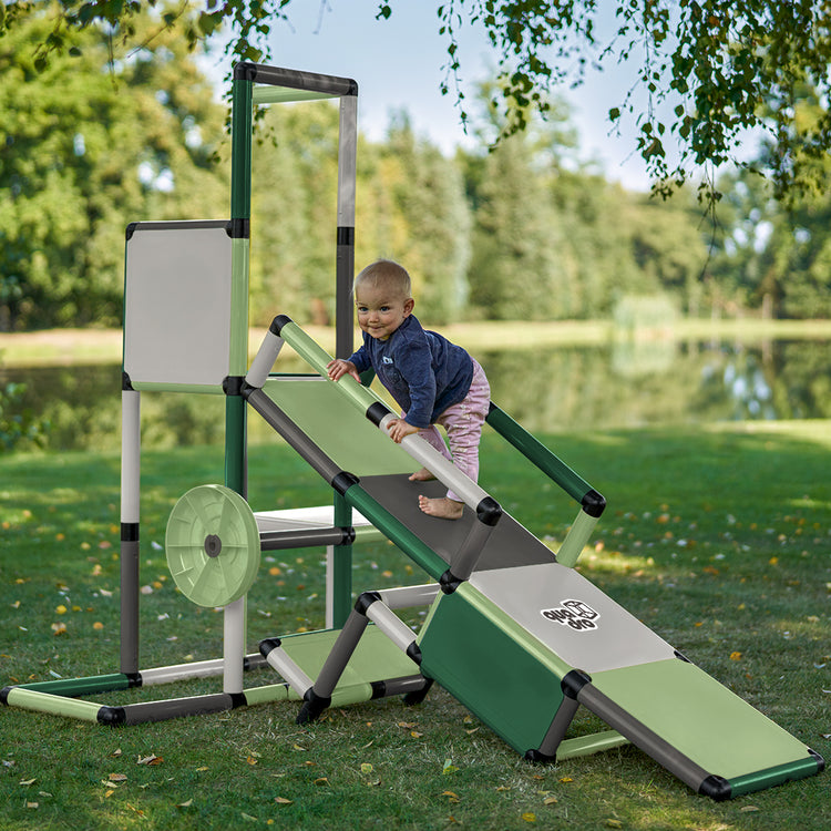 Małe dziecko boso trzyma się balustrady QUADRO Evolution Mint i wspina się po rampie na wieżę do zabawy